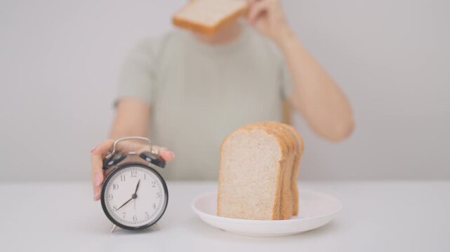 Happy smiling woman with whole wheat bread and alarm clock. concept of intermittent fasting, IF, meal timing, and choosing healthy carbohydrates for a balanced diet and weight loss management