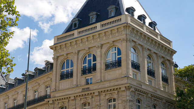 Parisian building displaying classic Haussmann architecture with decorative stone carvings under blue sky