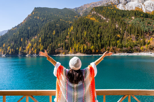 Young female tourist relaxing and enjoying at beautiful autumn scenery landscape at jiuzhaigou national park in Sichuan, China
