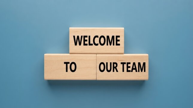 Welcome sign made from wooden blocks against a blue background with greeting message team spell out greeting officeenvironment workplaceculture