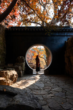 Young female tourist relaxing and enjoying the view of red maple leaves during the autumn foliage season at Suzhou, China
