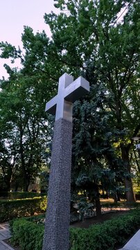 Pull back camera movement reveals a big iron cross at a park in the city of Warsaw. Vertical slow motion footage, WWII memorial.
