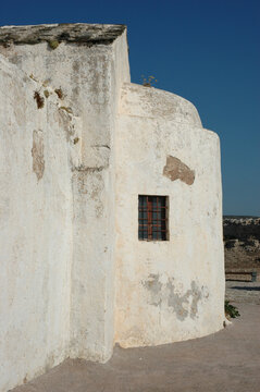 Traditional historic white apsidal facade of the Church of Panagia Myrtidiotissa with a small barred window stands inside Chora fortress on Kythira island
