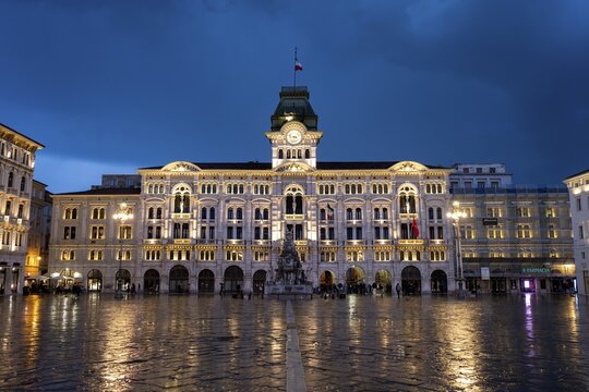 Illuminated square Piazza Unit&agrave; d'Italia, Town Hall, Palazzo Communale, with reflection, dramatic clouds, blue hour, old town, Trieste, Friuli-Venezia Giulia region, Italy