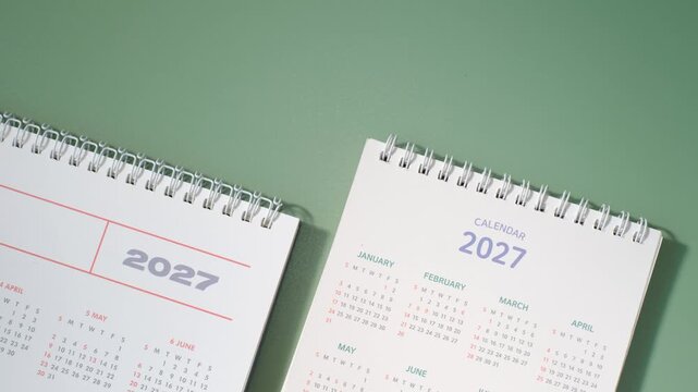 Calendars for 2027 on green background close-up top view.
