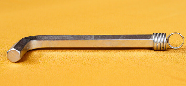 Silver hexagonal L-shaped key made of high-strength chrome vanadium alloy steel on a gold cloth background.
