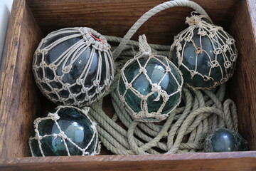 Vintage Japanese glass fishing floats with ropes inside an antique rustic wooden box. © Arai