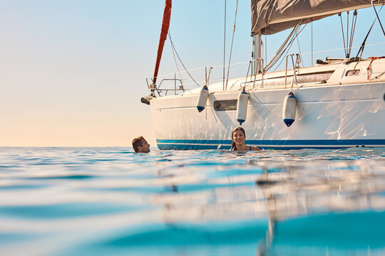 Boat, relax and swimming with couple in ocean together for holiday cruise, travel or voyage. Sailing, space and yacht with happy people in sea water for adventure, bonding or journey in summer