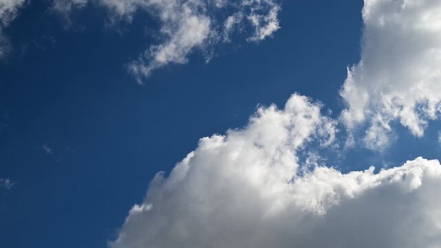 timelapse low angle view of blue sky peeking through openings in white cumulus clouds