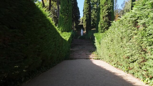 Steps on the shady alleys of Santa Clotilde Park in Lloret de Mar, Costa Brava, Spain - paths among green trees and bushes, statues