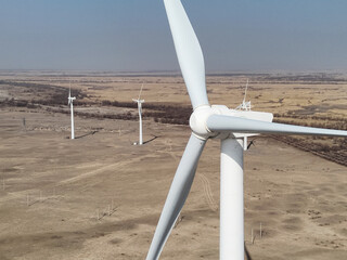 Close-up aerial view of wind turbine rotor and blades in desert for Sustainable green energy  © PakLam
