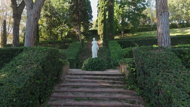 Steps on the shady alleys of Santa Clotilde Park in Lloret de Mar, Costa Brava, Spain - paths among green trees and bushes, statues
