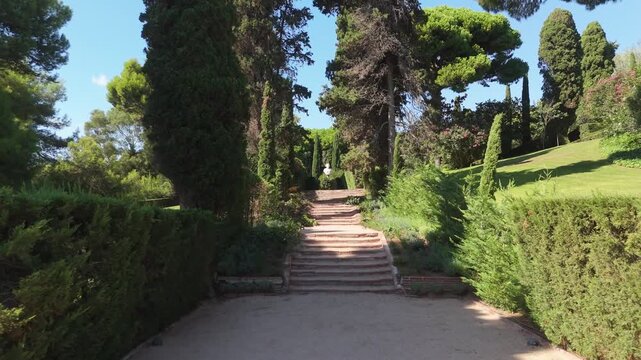 Steps on the shady alleys of Santa Clotilde Park in Lloret de Mar, Costa Brava, Spain - paths among green trees and bushes, statues