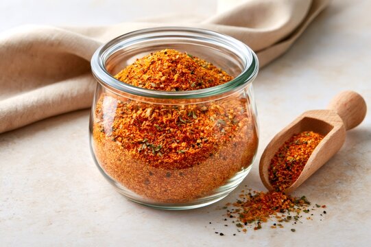 Chili seasoning mix in glass jar with wooden scoop