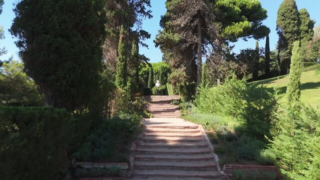 Steps on the shady alleys of Santa Clotilde Park in Lloret de Mar, Costa Brava, Spain - paths among green trees and bushes, statues
