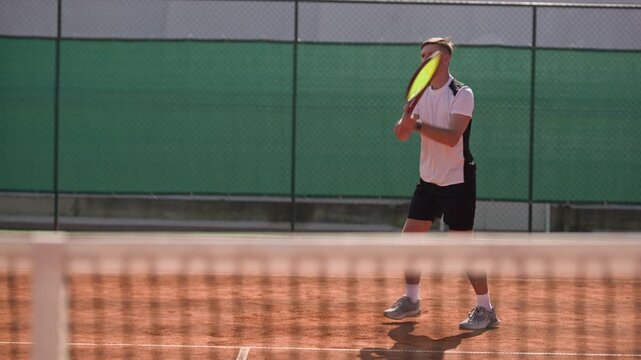 Caucasian young adult man hitting forehand and backhand shots during tennis match on clay court. Perfect for sports training campaigns and athletic lifestyle content