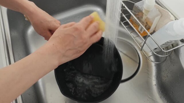 鍋を洗う女性の手元
