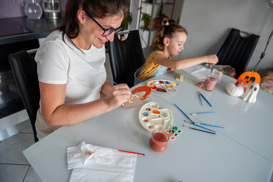 Mother and daughter paint Halloween decorations at home