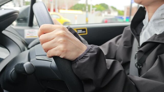 自動車のハンドルを握り運転する女性の手元