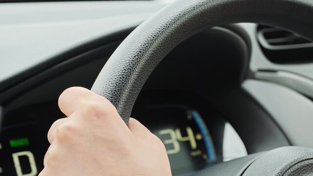 自動車のハンドルを握り運転する女性の手元