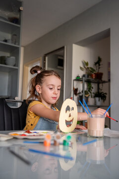 Girl create Halloween decoration at home with paint