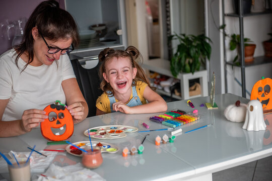 Mother and daughter smiling while making Halloween decorations at home