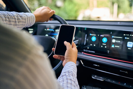 Driver holds smartphone inside connected car with dashboard