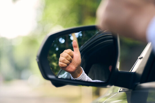 Driver give thumbs up from car side mirror