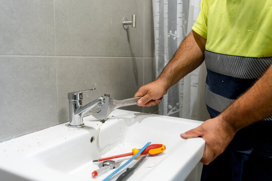 Plumber remove wall-mounted sink during bathroom renovation