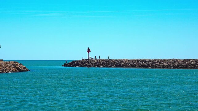 People are walking on the jetty by the water. Valras, France .