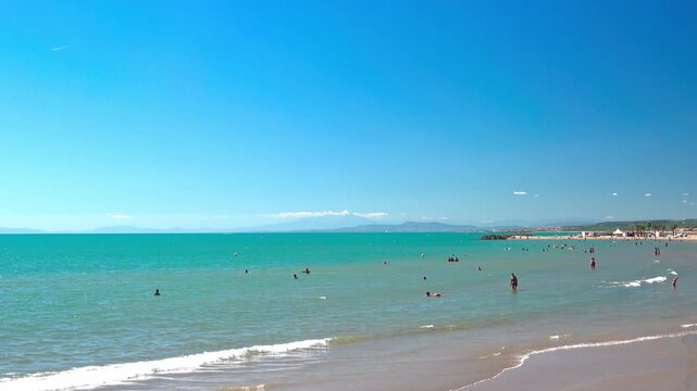 Families and friends enjoy sun and gentle waves. Valras, France .