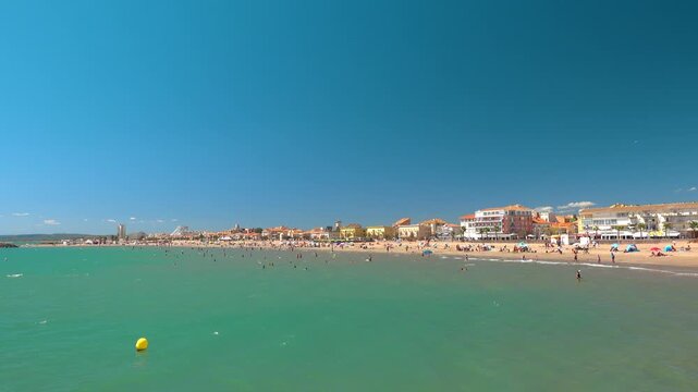 People are sunbathing and swimming at a beach. Valras, France .