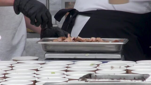 Cooks preparing and packaging food in an open street kitchen