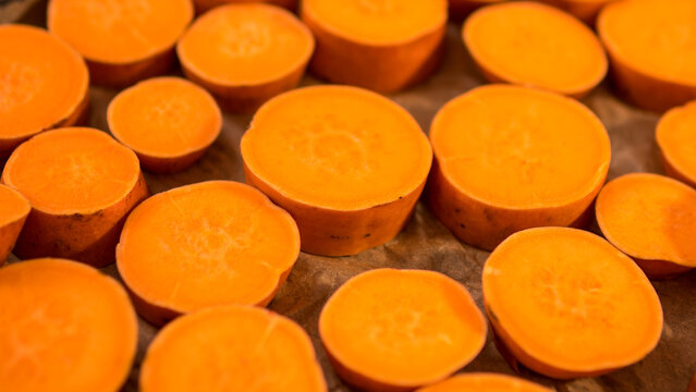 Raw Sweet Potato Slices Ipomoea batatas Arranged on Baking Paper Ready for Roasting &mdash; Concept: Healthy Plant Based Cooking, Meal Preparation Flat Lay, Vibrant Food Background