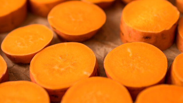 Raw Sweet Potato Slices Ipomoea batatas Arranged on Baking Paper Ready for Roasting &mdash; Concept: Healthy Plant Based Cooking, Meal Preparation Flat Lay, Vibrant Food Background