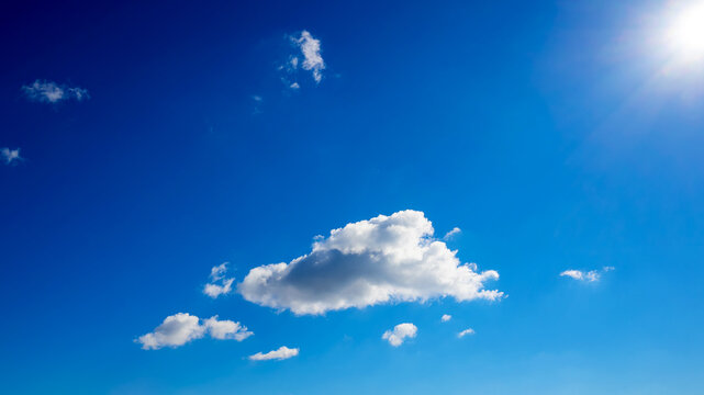 bright sun in the top corner illuminating a small cloud on a blue sky