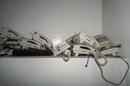 Pile of vintage telephones in dimly lit room