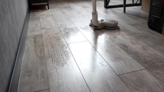 Advanced residential floor cleaning appliance with integrated rotating pads moving across a modern tiled interior surface during domestic maintenance tasks