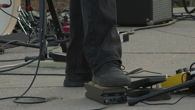 Guitarist on stage uses volume pedal to swell guitar sound, close-up