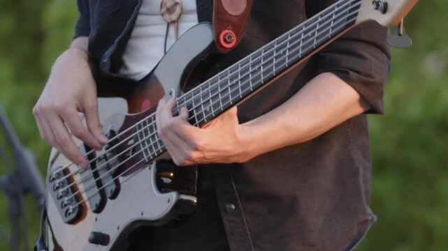 Bassist at outdoor performance plays solo on 5-string electric bass