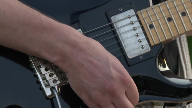 Closeup strumming technique: Guitarist playing black electric guitar