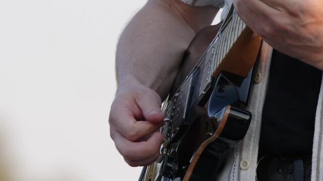 Close-up technique: Guitarist plays electric guitar against white sky