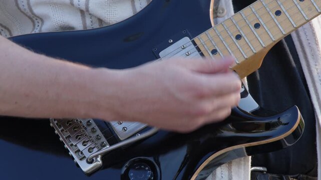 Close up: Guitarist plays electric guitar at outdoor gig, whammy bar