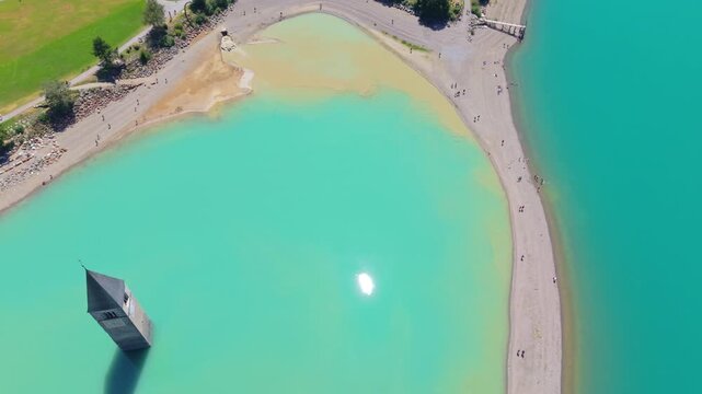 Aerial top down view of the iconic submerged church tower of Curon Lake Resia, in South Tyrol, Italy drone fly above the bell tower , famous travel destination