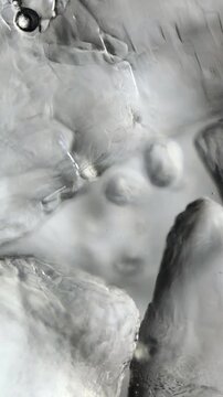 Sugar crystal dissolves slowly in water under microscope. Selective focus moves smoothly from near crystals to far ones