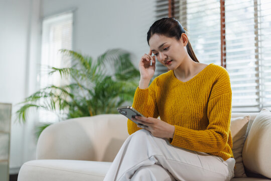 Woman experiencing stress using smartphone at home