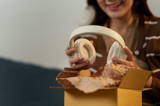Happy woman unboxing new wireless headphones received from online shopping delivery