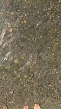 Small Waves Washing Over Bare Feet in Clear Shallows