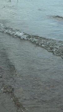 Gentle Waves Washing Over a Sandy Shore in Daylight