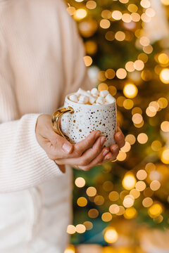 Hands holding cup cocoa marshmallows Christmas lights